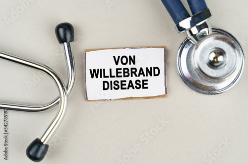On a gray background, a stethoscope and a cardboard sign with the inscription - Von willebrand disease