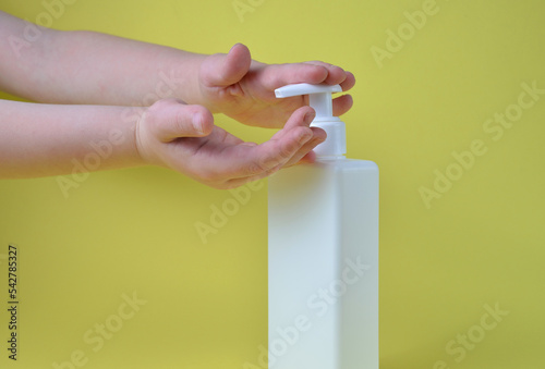 The hands of the child press the bottle of soap.