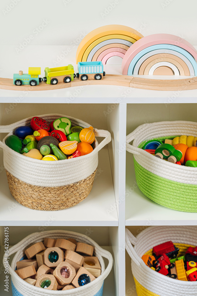 Colorful storage baskets on shelves. White shelving with rainbow wooden  toys in cloth stylish baskets. Organizing and storage ideas in nursery.  Interior design. Stock Photo | Adobe Stock