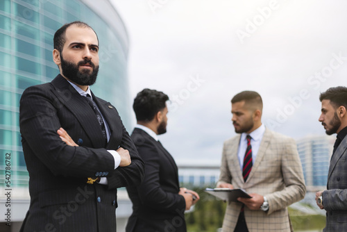 Business people outdoor meeting. Portrait of a business man against the background of a group of people and buildings of the city center