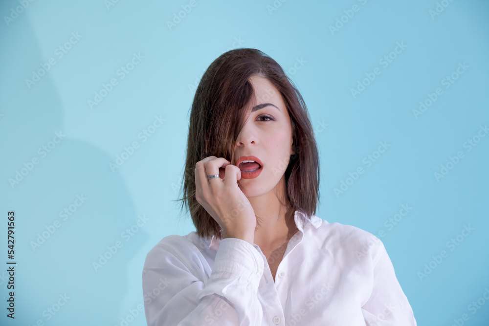 Close-up portrait of beautiful sensual caucasian woman with brown hair wearing white shirt. Blue background. Selective focus. People theme. Close-up portrait of beautiful sensual caucasian woman with brown hair wearing white shirt. Blue background. Selective focus. People theme.