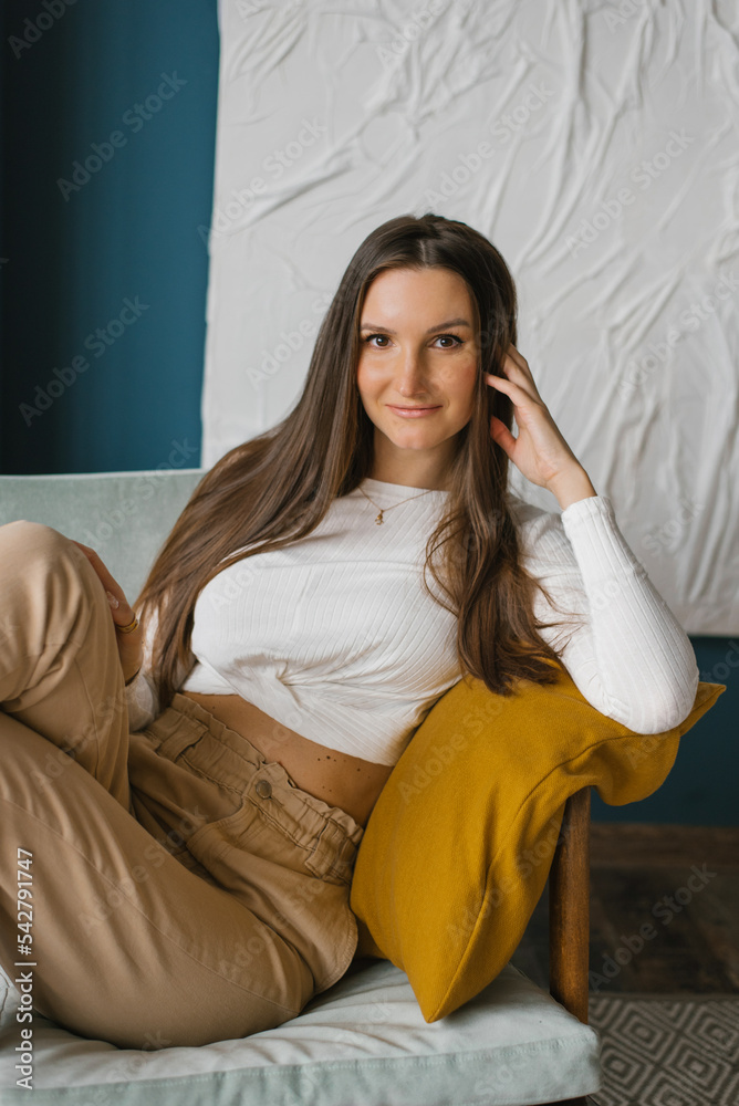 Happy woman is sitting on a chair at home leaning on her arm Happy woman is sitting on a chair at home leaning on her arm