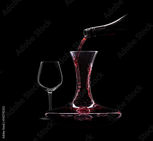 Canvastavla Pouring red wine from bottle to decanter isolated on black background