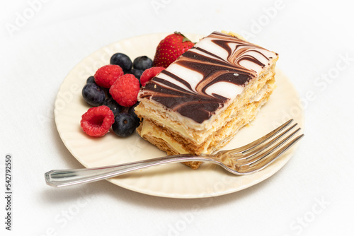 Napoleon dessert pastry and colorful mixed berries plated with silver fork.