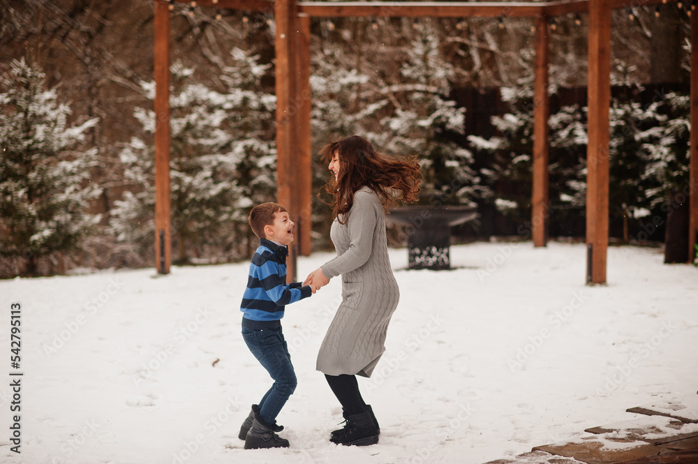 Mother with son jumping in winter day, spending time together.