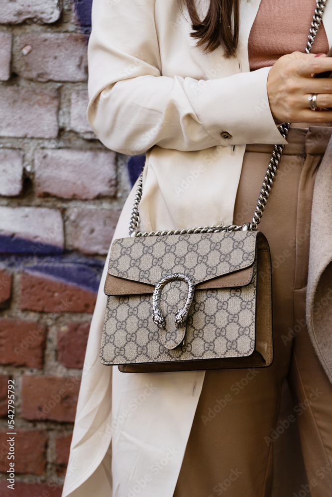 Milan, Italy - September, 21, 2022: woman wearing beige and brown GG  monogram print pattern crossbody bag from Gucci, Dionysus GG Supreme mini  bag, street style outfit details. Stock-Foto | Adobe Stock