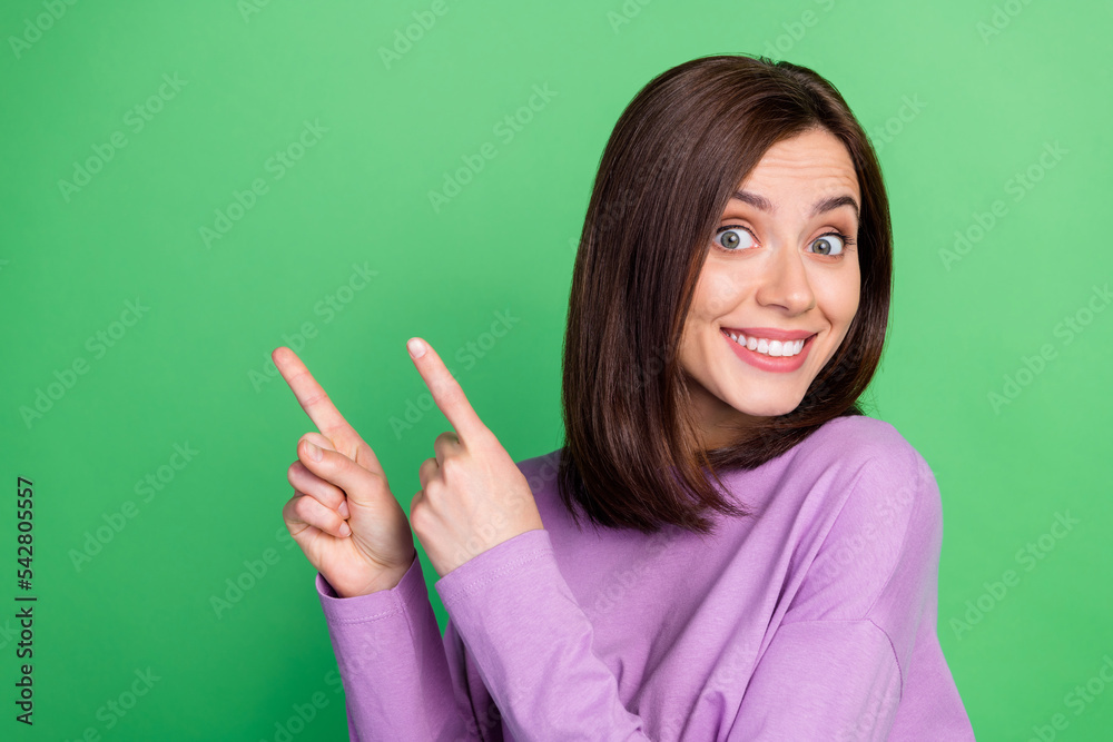 Closeup photo of young stunning cute girl toothy smile direct fingers empty space isolated on green color background Closeup photo of young stunning cute girl toothy smile direct fingers empty space isolated on green color background