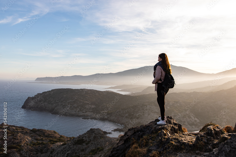 Beautiful women standing on a cliff during sunset with the sea on the background