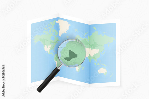 Enlarge Mali with a magnifying glass on a folded map of the world.