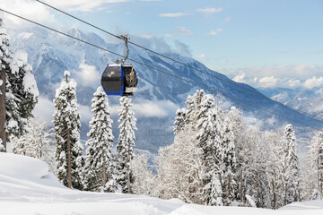 New modern spacious big cabin ski lift gondola against snowcapped forest tree and mountain peaks covered in snow landscape in luxury winter alpine resort. Winter leisure sports, recreation and travel