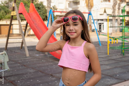 Cute happy child girl wearing sunglasses in a park outdoors.