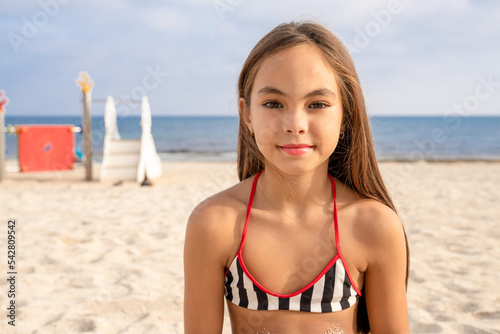Close up of Little cute child girl in on the beach with smile on summer vacation. Happy children kid enjoy and fun outdoor activity lifestyle