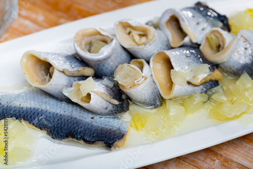 Rolled herring in vinegar, served with onions on a white ceramic plate in a restaurant