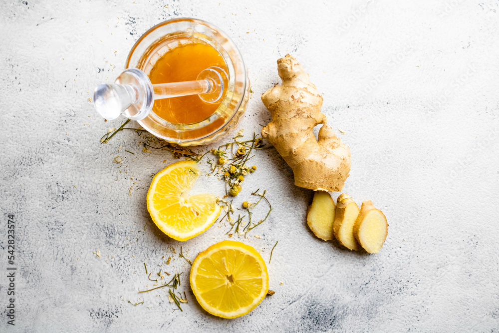 Slices of yellow Sicilian lemon, ginger, honey and chamomile on branch and flower. Mention health care, alternative medicine with fruits, herbs and plants, treatment of diseases and symptoms. Slices of yellow Sicilian lemon, ginger, honey and chamomile on branch and flower. Mention health care, alternative medicine with fruits, herbs and plants, treatment of diseases and symptoms.