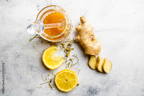 Slices of yellow Sicilian lemon, ginger, honey and chamomile on branch and flower. Mention health care, alternative medicine with fruits, herbs and plants, treatment of diseases and symptoms.