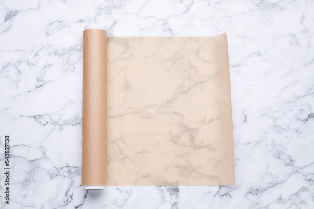 Roll of baking paper on white marble table, top view