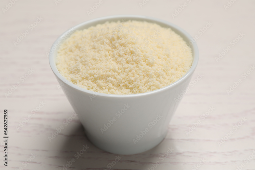 Delicious grated parmesan cheese in bowl on white wooden table Delicious grated parmesan cheese in bowl on white wooden table