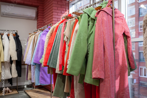 Colorful women's dresses, jackets, trousers and other clothes on hangers in a retail store. The concept of fashion and shopping. Women's clothing boutique.