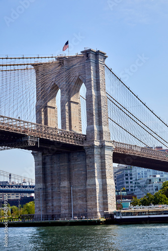 Famous Brooklyn Bridge going from Brooklyn to Manhattan in New York City viewing from the river on a lovely fall day