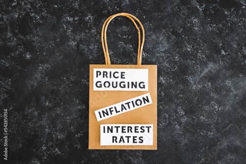 Inflation Interest Rates and Price Gouging texts on paper shopping bag, symbol of excessive pricing