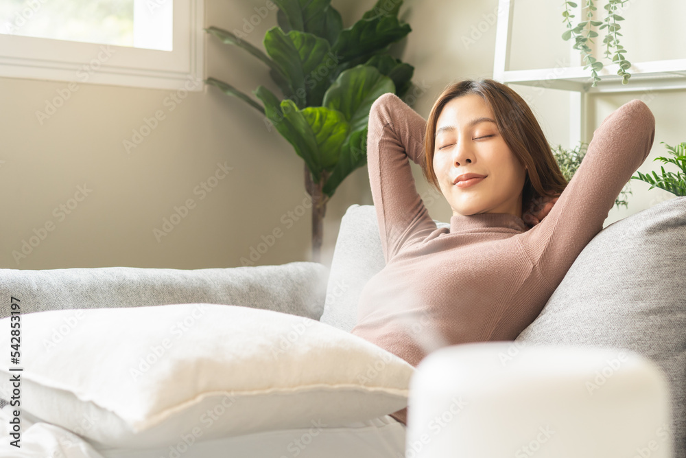 Modern air humidifier during relax or rest, happy asian young woman, girl enjoying aromatherapy steam scent from essential oil diffuser comfortable in living conditions room, apartment at home. Modern air humidifier during relax or rest, happy asian young woman, girl enjoying aromatherapy steam scent from essential oil diffuser comfortable in living conditions room, apartment at home.
