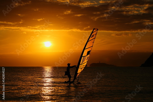 夕暮れの逗子海岸、オレンジに染まる海でウィンドサーフィンを楽しむ若者 © Takeru