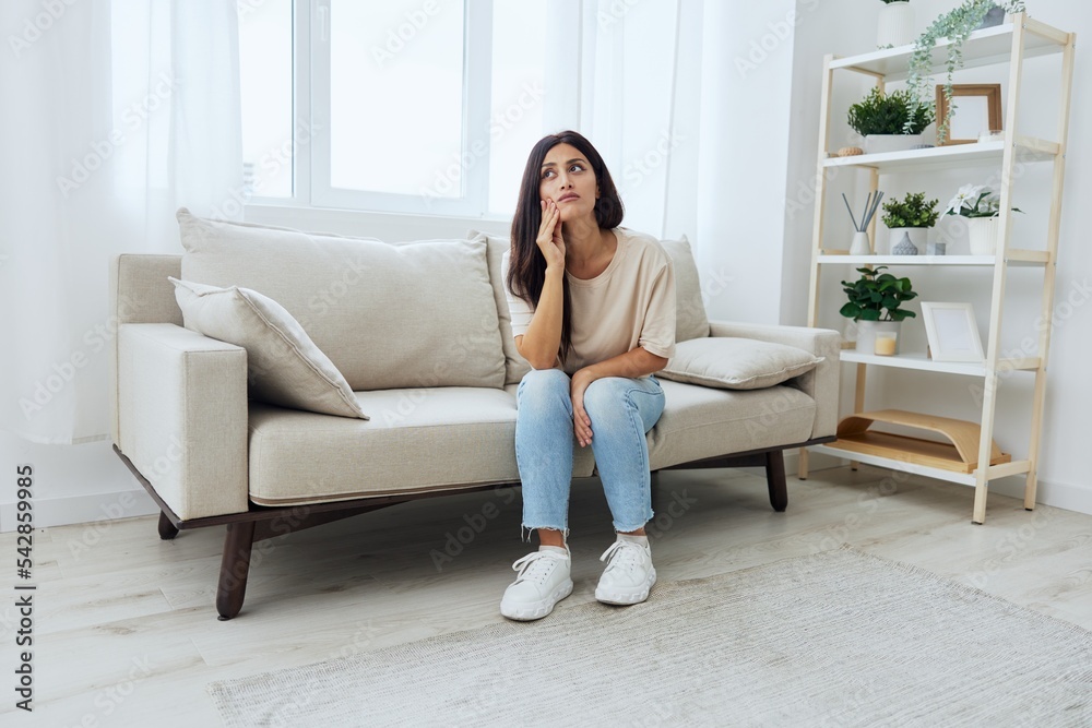 Woman toothache, tooth root inflammation sitting on sofa at home Woman toothache, tooth root inflammation sitting on sofa at home