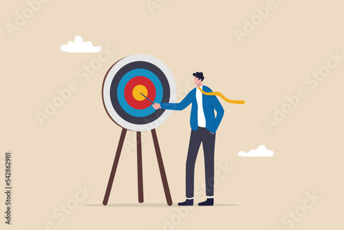 Specific goal, clarify objective or target, focus or concentrate on purpose to win business mission, perfection or aiming at target concept, businessman pointing at center of bullseye archery target. photo
