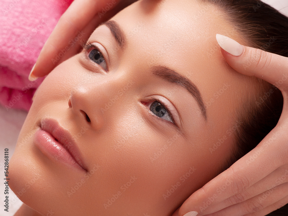 Young girl with thick eyebrows and perfect skin at white background, towel on head, beauty photo concept, skin care, spa concept, treatment, facial massage. Young girl with thick eyebrows and perfect skin at white background, towel on head, beauty photo concept, skin care, spa concept, treatment, facial massage.