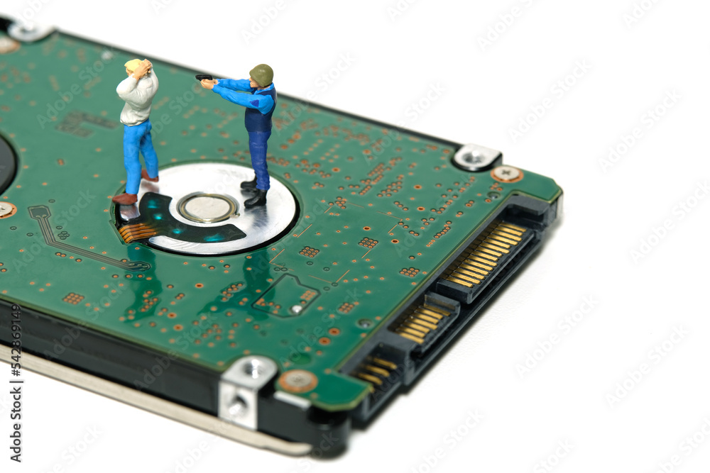 Miniature people toy figure photography. Data protection concept. A security officer capturing a thief above external disk drive. Isolated on white background Miniature people toy figure photography. Data protection concept. A security officer capturing a thief above external disk drive. Isolated on white background