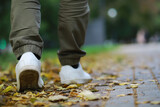 Feet sneakers walking on fall leaves Outdoor with Autumn season nature on background Lifestyle Fashion trendy style