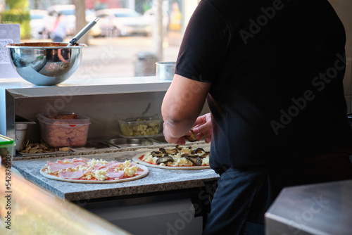 Unrecognizable male preparing pizzas in a restaurant kitchen. Pizzeria.
