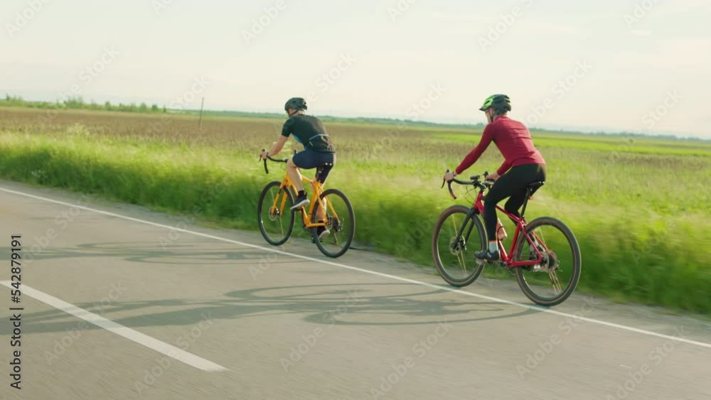 Active caucasian men in sportswear and helmet spending time for outdoor cycling with green summer field on background. Concept of people and workout. Active caucasian men in sportswear and helmet spending time for outdoor cycling with green summer field on background. Concept of people and workout.