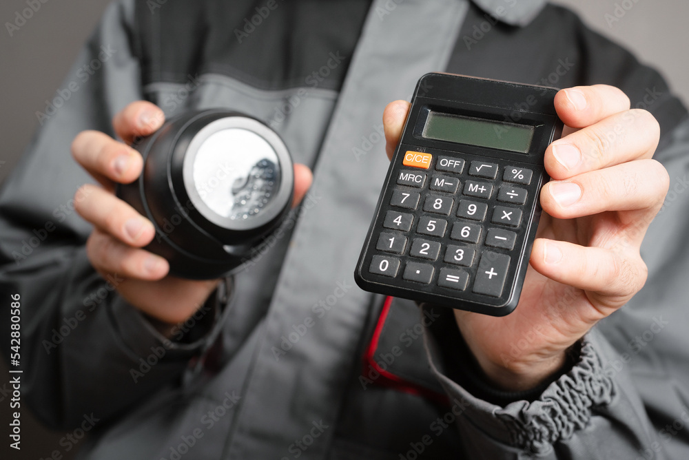 Calculation of the cost of installation of a video surveillance system concept. Video surveillance service worker holds a cctv security camera and calculator close up. Calculation of the cost of installation of a video surveillance system concept. Video surveillance service worker holds a cctv security camera and calculator close up.