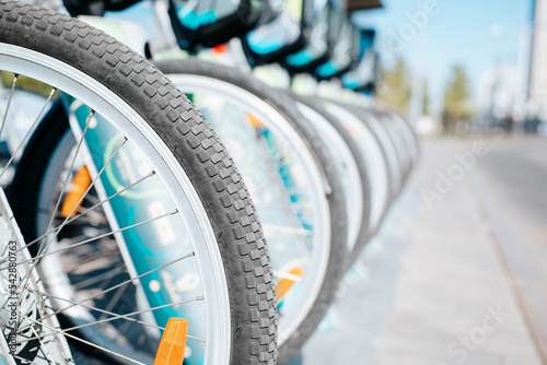 Bicycles for rent. Vehicles parked in a row, close-up of bicycle wheels outdoors
