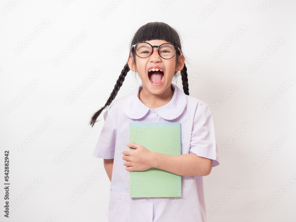 Funny student girl 6 year old wearing a school uniform and holding a book on hand. Primary school lovely kid with happiness. Back to school. Funny student girl 6 year old wearing a school uniform and holding a book on hand. Primary school lovely kid with happiness. Back to school.