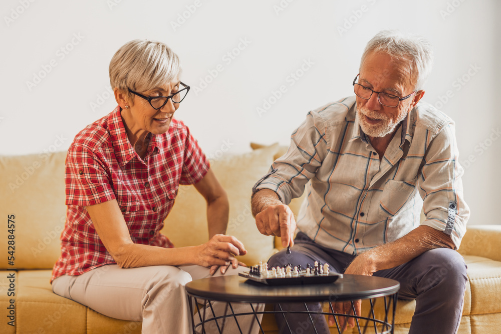 Senior couple sitting in living room and playing chess. Leisure activity. Senior couple sitting in living room and playing chess. Leisure activity.