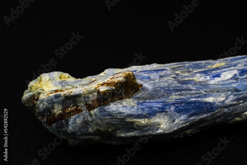 Raw vibrantly blue kyanite crystal stone chunk close up isolated on black surface background