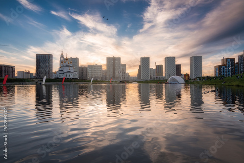Yekaterinburg city skyline. Buildings of the Academichesky district reflects in water of the pond at beautiful sunset