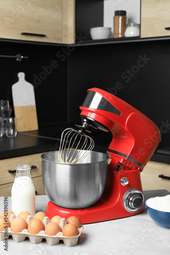 Modern stand mixer and ingredients on table in kitchen. Home appliance