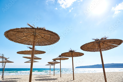 Fototapeta Naklejka Na Ścianę i Meble -  Beach wooden umbrellas on sand by sea