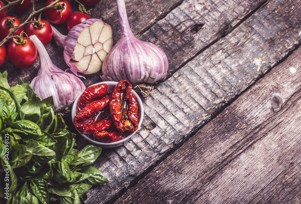 Dried tomatoes with garlic and herbs on a wooden background