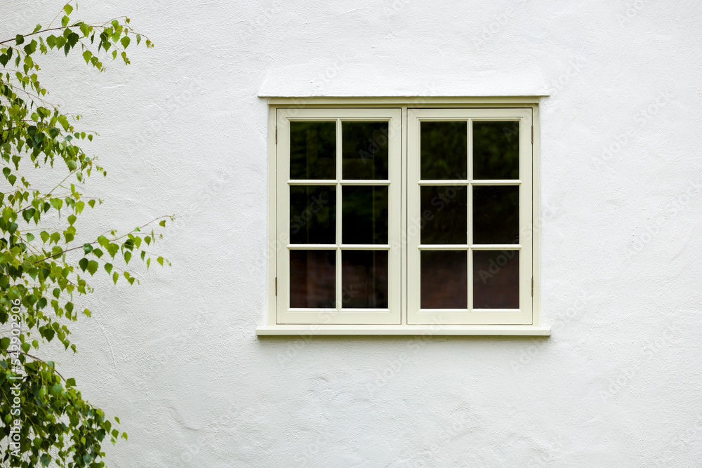 House exterior with wooden window and white wall rendering, UK