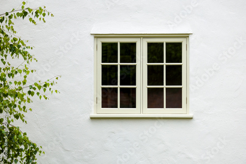 House exterior with wooden window and white wall rendering, UK