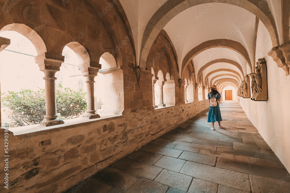 A girl traveler and tourist in the arch of an ancient monastery or the courtyard of the cathedral