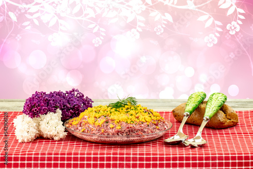 Traditional russian layered salad named herring under a fur coat. Traditional Russian cusine on a rustic table over abstracrt flower background. Concept Russian food. Space. photo