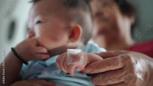 Grandmother hold the hand of baby after vaccination