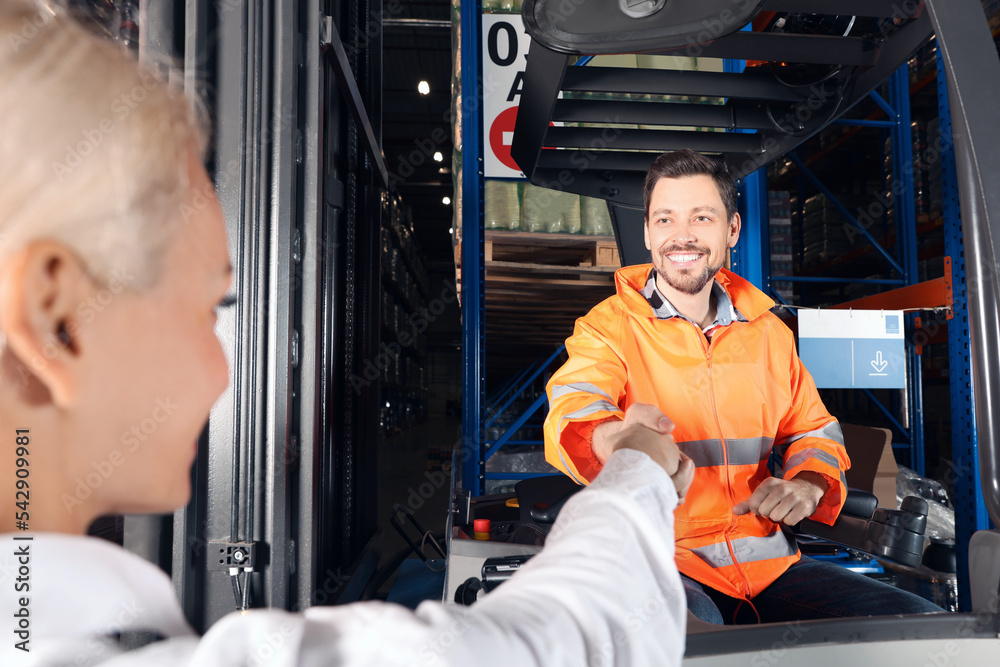 Happy worker shaking hands with manager in warehouse Happy worker shaking hands with manager in warehouse