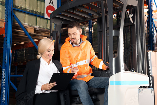 Worker talking with manager while sitting in forklift truck at warehouse © New Africa