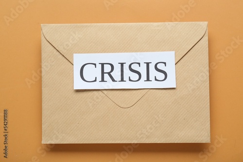 Envelope with word Crisis on brown background, top view photo